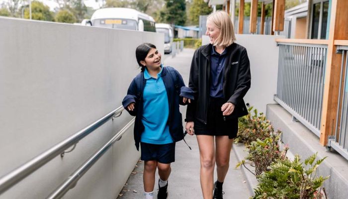 A student and a staff member walking into the school together while engaged in conversation
